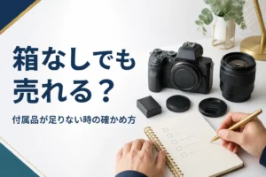 元箱の無い一眼レフと交換レンズの付属品を並べ、足りない物をメモに書き出している手元