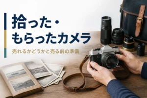 テーブルの上の古いフィルムカメラと写真アルバムを手に取る様子