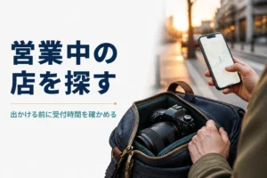 カメラバッグを持ちながらスマートフォンの地図で店を探す手元