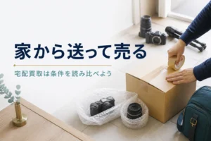 コンパクトデジカメと交換レンズを箱に詰め、宅配で送る準備をしている手元