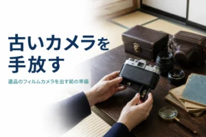古いフィルムカメラと革ケース、レンズを座卓に並べ、電池室を確かめて買取の準備をしている様子
